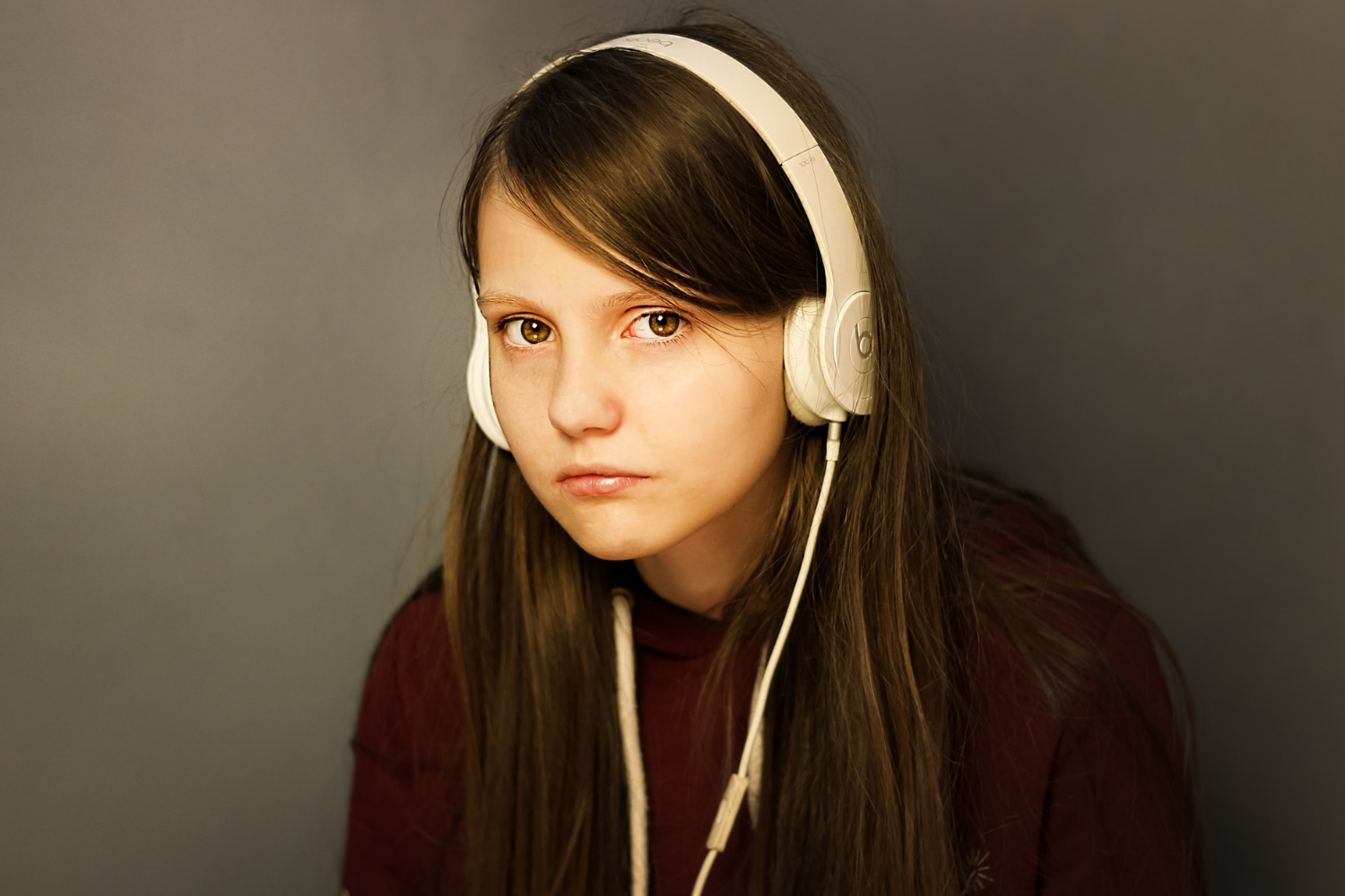 A young teenage girl with a sullen expression, listening to music