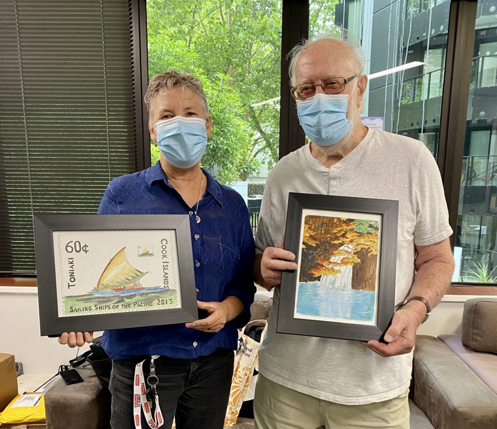 River and David holding up a piece of art each, posing mid frame for the camera