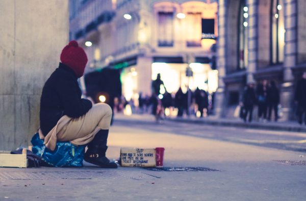 Homeless person sitting on street looking cold